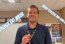 Man in a blue shirt standing in front of a classroom, holding a marker, talking about college go week.